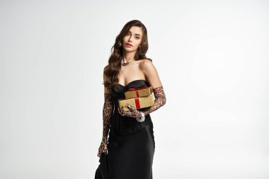 Göz kamaştırıcı genç kadın zarif bir moda sergilerken güzel paketlenmiş hediyeler tutuyor..