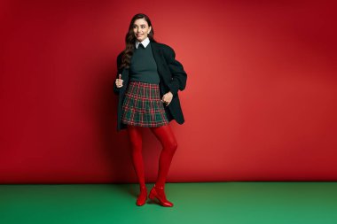 Çekici bir kadın şık bir elbise içinde şık bir poz verir. İçeriden neşe ve tatil ruhu yayar.