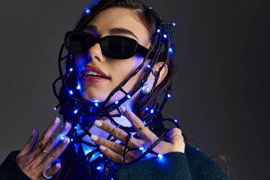 Genç kadın, canlı mavi ışıklar arasında yaratıcılık ve tarz sergiliyor.