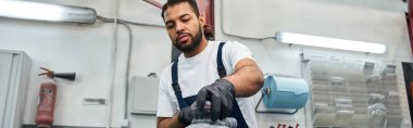Yetenekli bir tamirci iyi donanımlı bir garaj ortamında araba parçalarını tamir etmeye odaklanır..