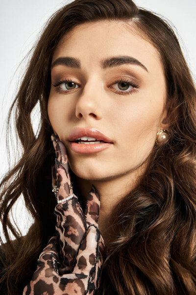 Young woman with wavy hair and elegant gloves showcases her beauty and confidence in style.