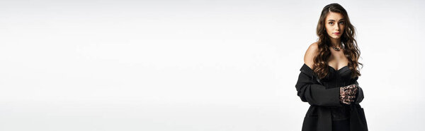 A pretty young woman stands elegantly in a chic outfit, showcasing grace and poise.