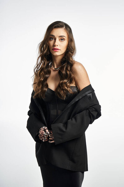 Young woman exudes elegance while wearing a sleek black outfit, radiating confidence and charm.