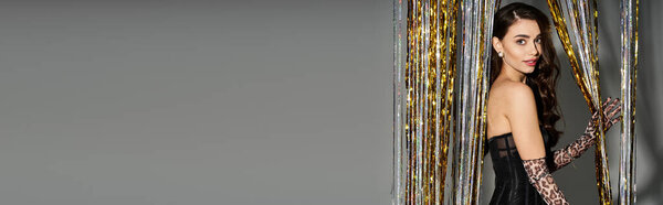 Young woman with long hair showcases stylish outfit against a backdrop of glimmering decor