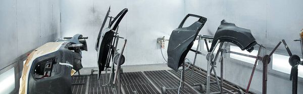 Some car parts in a bustling and well lit workshop.