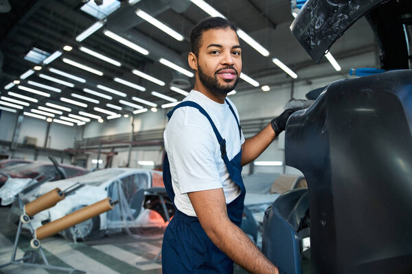 Красавчик механик фокусируется на ремонте в окружении транспортных средств и инструментов в занятой мастерской