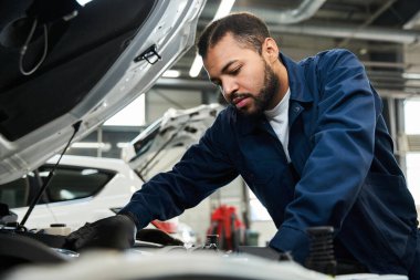 Yetenekli tamirci araçlarla dolu bir oto tamirhanesinde motor parçalarını tamir etmeye odaklanıyor.