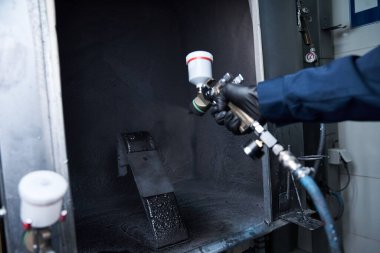 Yakışıklı genç bir tamirci, iyi donanımlı bir atölyedeki bir parçaya özenle boya sıkar..