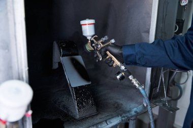 Kendini adamış tamirci, bir araç parçasına özen ve dikkatle taze boya uygular..