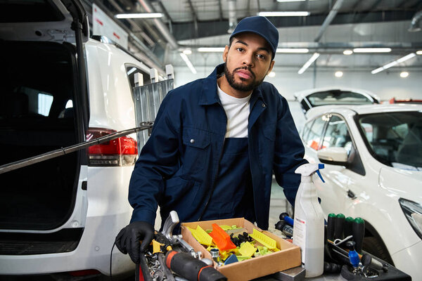 Выделенный механик фокусируется на задачах по техническому обслуживанию в окружении различных инструментов и транспортных средств.