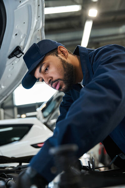 Красавчик-механик занимается ремонтом в хорошо освещенном современном гараже в дневное время.