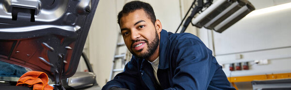 Young mechanic inspects a car engine with focus and skill in a bright garage during work hours.