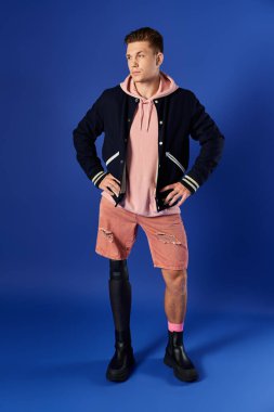 Young man showcasing a fashionable look with a prosthetic leg against a vibrant blue backdrop. clipart