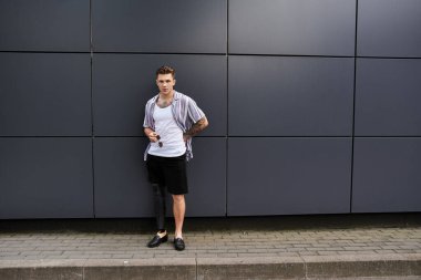 Protez bacaklı genç adam modern bir duvara yaslanıyor, kendine güveni ve tarzı var..