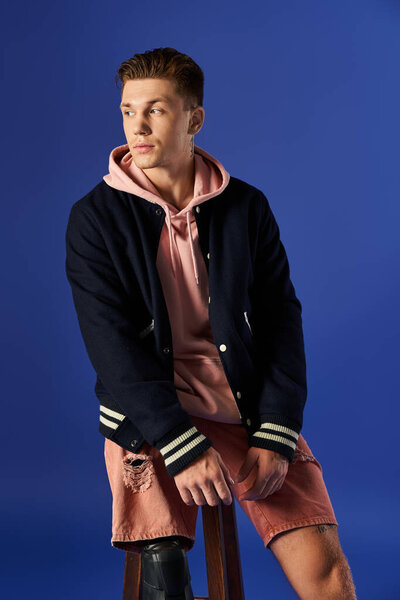 A young man in a stylish outfit sits on a stool, confidently showing off his prosthetic leg.