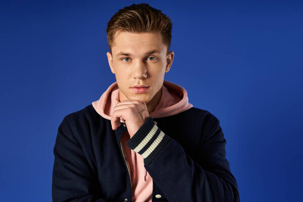 Young man shows confidence and thoughtfulness in a striking blue setting.