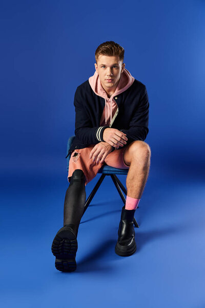 Young man sits confidently on a chair, showcasing his stylish outfit and prosthetic leg.