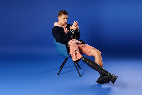 Handsome young man relaxes while confidently displaying his prosthetic leg in a modern setting.