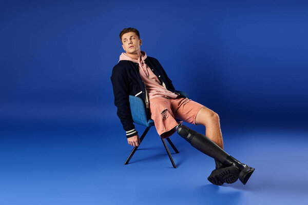 A young man relaxes in trendy clothes, proudly showcasing his prosthetic leg.