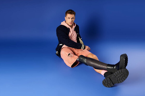 Young man sits with a prosthetic leg, showcasing style and confidence in a relaxed pose.