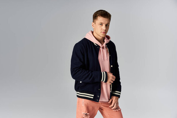 Young man poses stylishly in a casual outfit against a simple backdrop.