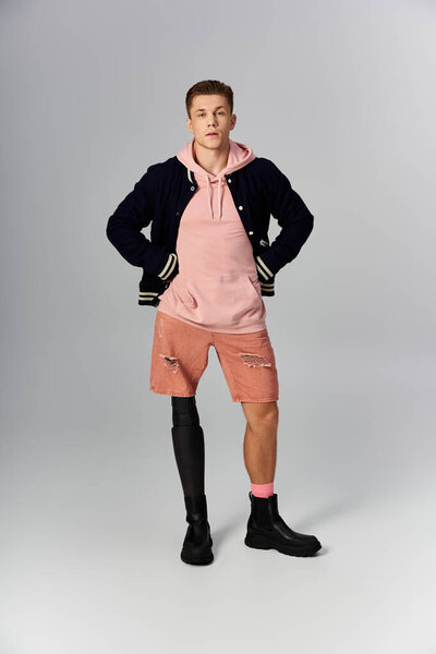 Молодой человек в повседневной одежде уверенно демонстрирует свою протезную ногу, олицетворяя стойкость.