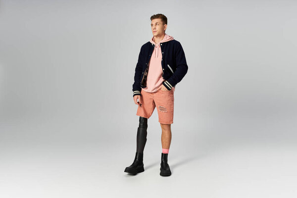 Young man stands tall, wearing a stylish outfit and proudly displaying his prosthetic leg.