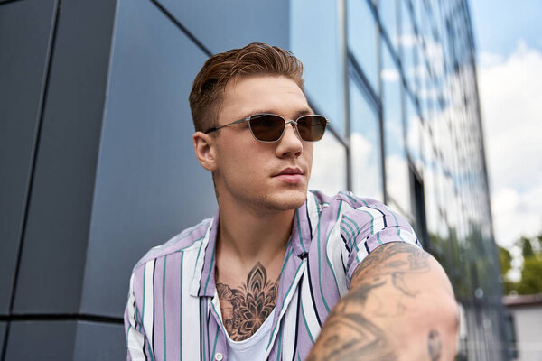 Молодой человек расслабляется возле шикарного городского здания в светлый день.