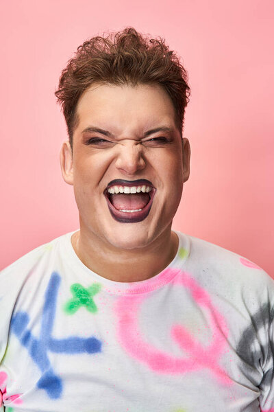 Individual joyfully smiles while showcasing vibrant makeup and colorful attire.