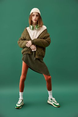 Güzel genç bir kadın kendine güvenerek yeşil bir yerde poz verir ve kendine has tarzını sergiler..