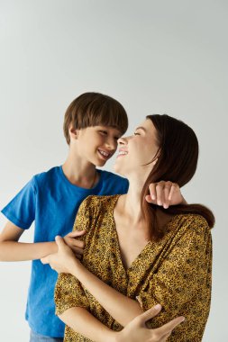 A young mother shares a warm, joyful moment with her son in a cozy studio. clipart