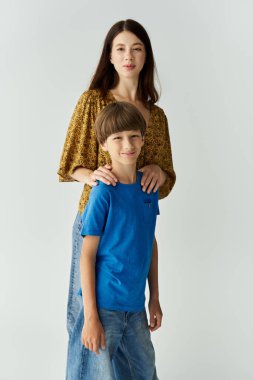 Genç bir anne hem günlük giysiler içinde hem de aile sevgisini ve sıcaklığını yayarak oğlunun yanında duruyor..