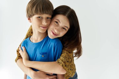 A young mother and her son share a warm embrace, showcasing their bond in a stylish studio. clipart