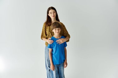 A young mother and her son share a warm embrace in casual outfits in a studio. clipart