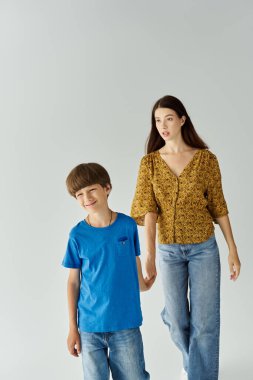 Bir anne ve küçük oğlu, parlak bir stüdyoda günlük kıyafetlerini giyerken neşe içinde etkileşime girerler..