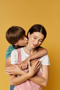 Genç bir anne, yanağından öpen oğlunu sevgiyle kucaklıyor..