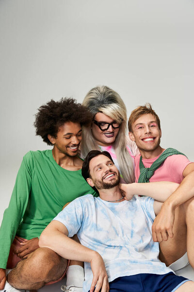 Группа из четырех друзей радостно позируют вместе, демонстрируют яркие наряды и улыбки.