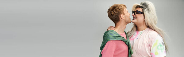 Two individuals express affection and happiness, embodying queer joy in a colorful setting.