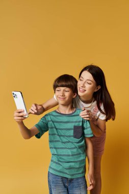 Genç bir anne ve oğlu birlikte selfie çekmekten zevk alırlar, neşeli bağlarını gösterirler..