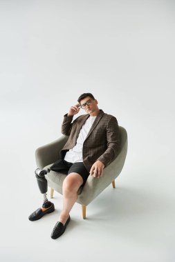 Handsome young man poses in a chair, showcasing his stylish outfit and prosthetic leg. clipart