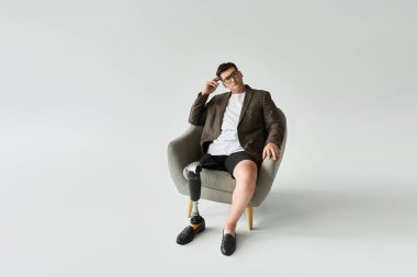 Protez bacaklı genç bir adam, derin düşüncelere dalmış, modern bir sandalyede oturuyor..