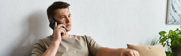 Handsome young man talks on the phone while sitting comfortably.