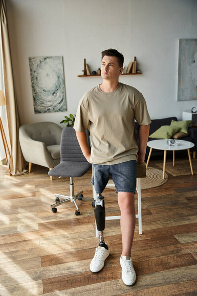 Красивый молодой человек демонстрирует свою протезную ногу, расслабляясь в стильной гостиной.