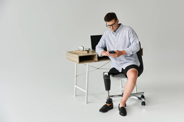 Handsome young man interacts with smartphone while seated at a desk in a bright space.