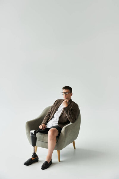 Handsome young man poses in a stylish chair while showcasing his prosthetic leg