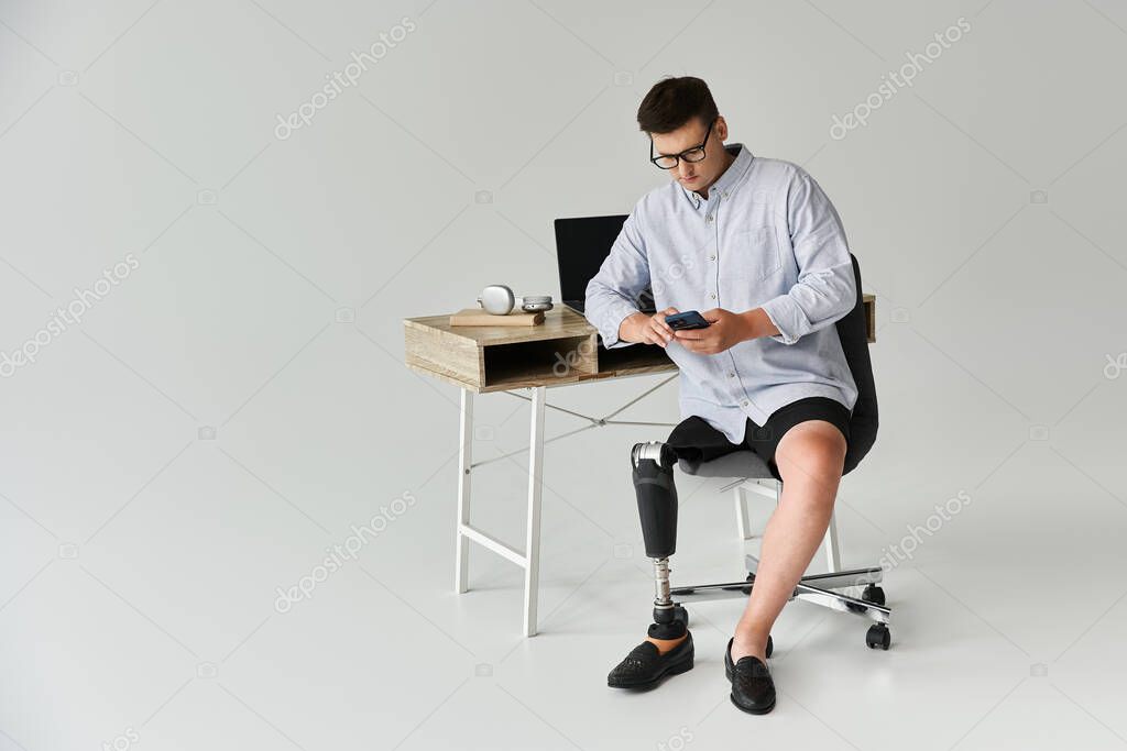 Handsome young man interacts with smartphone while seated at a desk in a bright space.