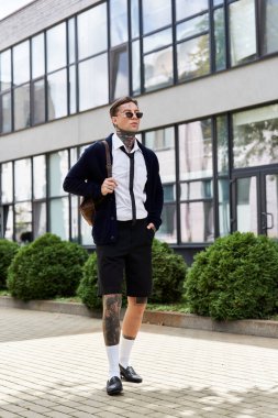 Dövmeli şık genç adam, günışığında çağdaş mimarinin yanından rahatça geçiyor..