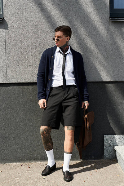 Handsome young man in stylish attire stands confidently against a textured wall