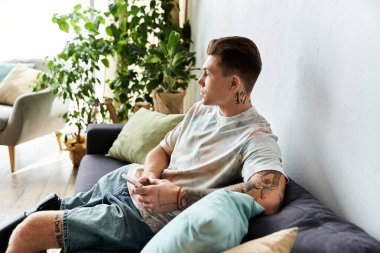 Yakışıklı genç adam, canlı bir yerde telefon tutarken koltukta sakin vakit geçirmekten zevk alıyor..