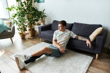 Genç adam yumuşak bir halıya uzanıyor, eşsiz stilini ve dayanıklılığını sergiliyor..